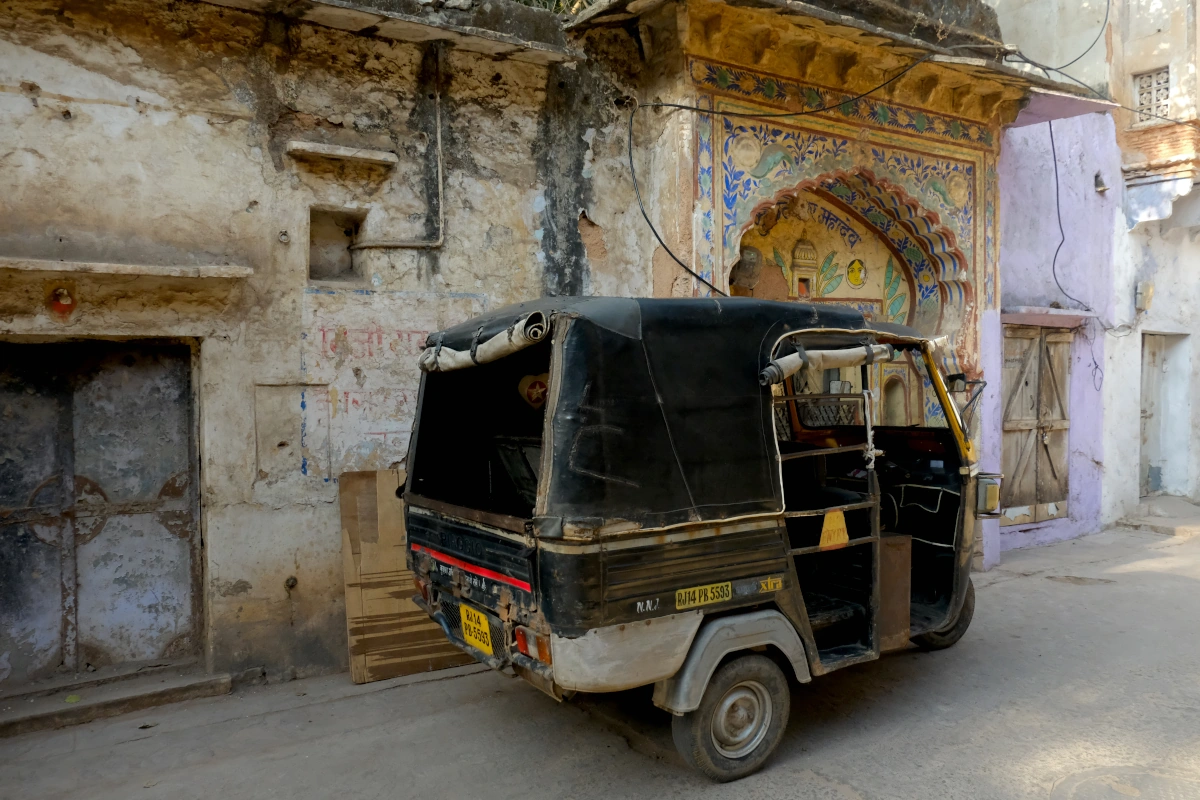 Tuk-tuk devant une maison ornée de peintures murales colorées dans un village du Rajasthan, en Inde.