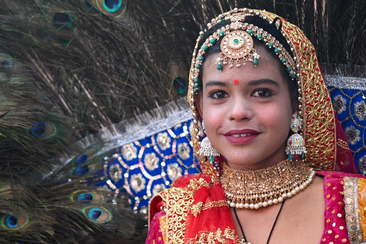 Jong meisje in traditioneel kostuum met pauwenveren op de kamelenmarkt van Pushkar, Rajasthan, India.